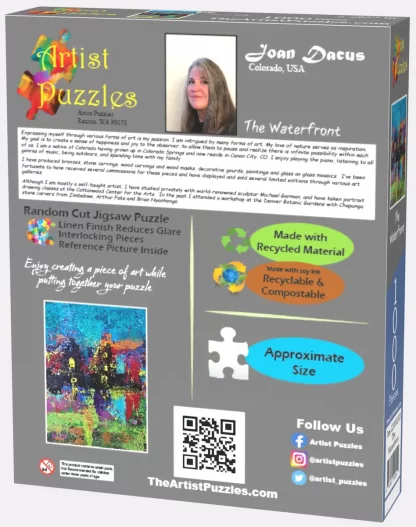 Box back of Artist Puzzles The Waterfront jigsaw puzzle. A picture of and bio info about the artist – Joan Dacus, a small pic of the puzzle, a pic of a puzzle piece showing the actual size of the pieces, social media links, and a QR code.